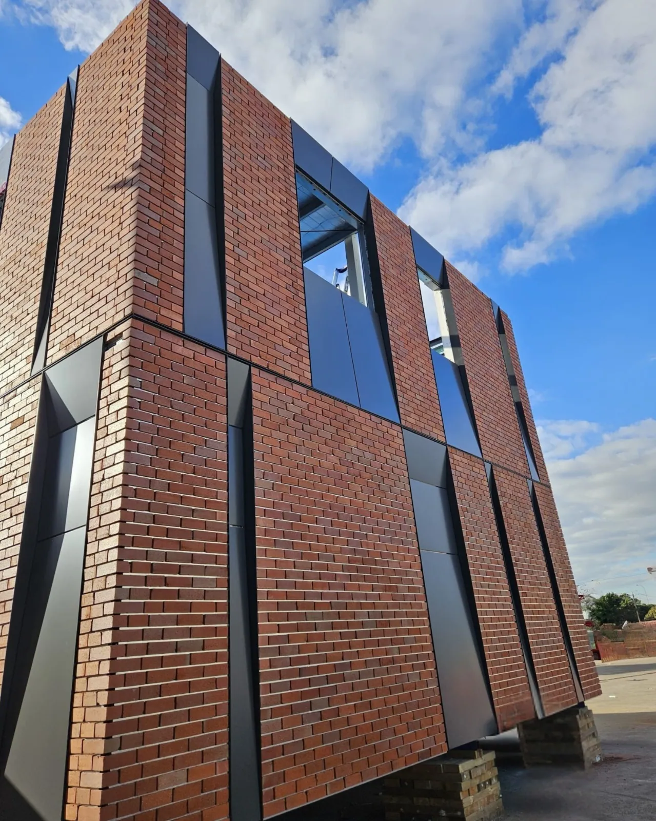 Red brick and rail facade system panels on a multi-residential building